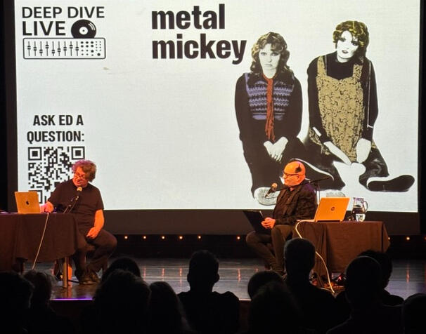 Metal Mickey — Ed Buller talks through the making of Metal Mickey by Suede Ed Buller and interviewer Simon Price seated on stage with a black-and-white photo of Metal Mickey single artwork displayed on the screen behind them.